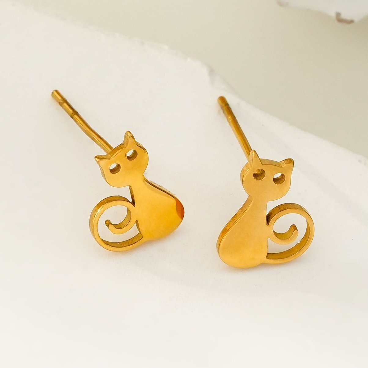Gold cat-shaped earrings on a white background