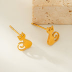 Gold cat-shaped earrings on a beige background
