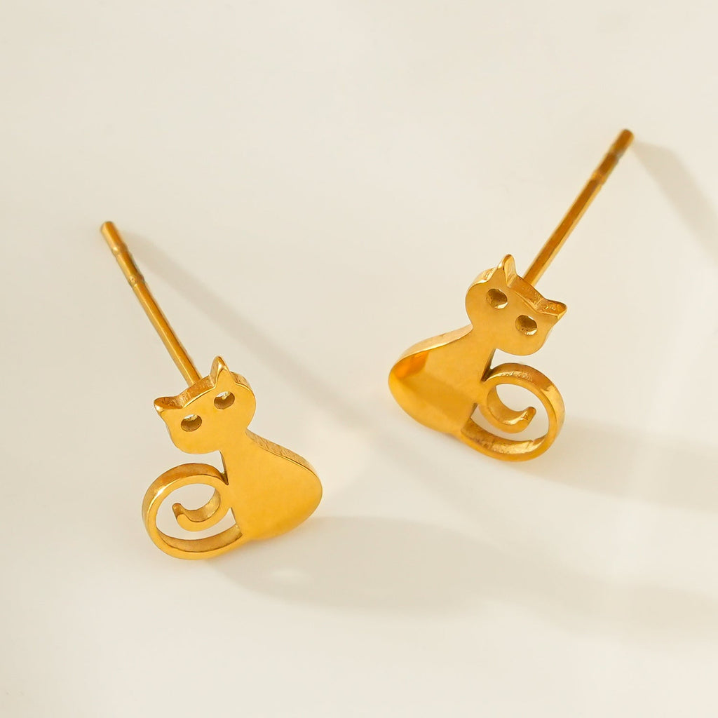 Gold cat-shaped earrings on a light beige background