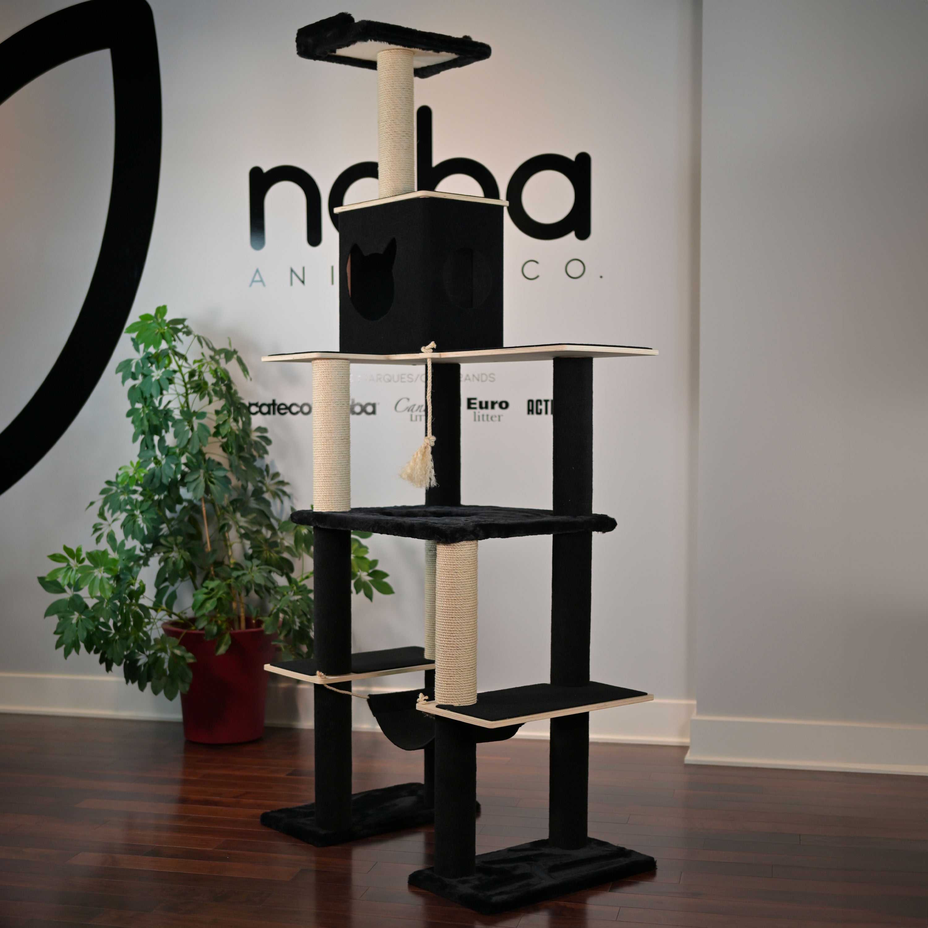 Cat tree with multiple levels and a hammock in front of a branded wall.