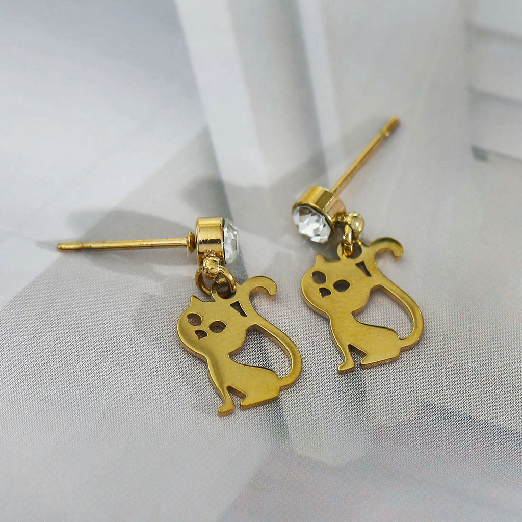 Gold cat-shaped earrings with a clear gemstone on a light gray background