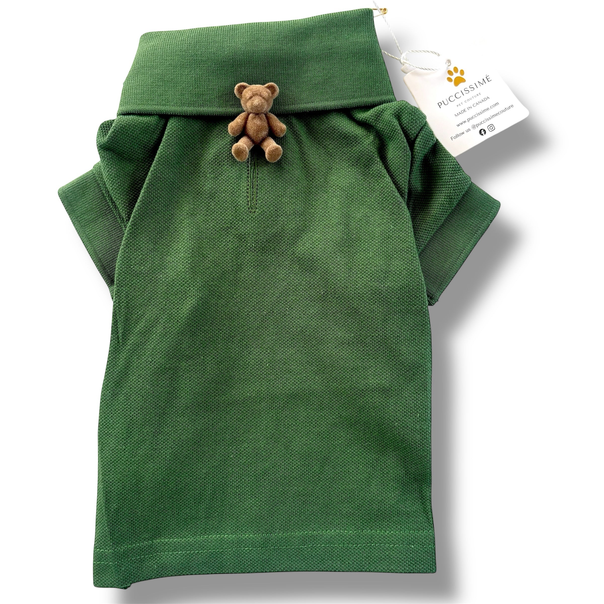 Green dog polo shirt with a teddy bear charm and a visible brand tag on a white background