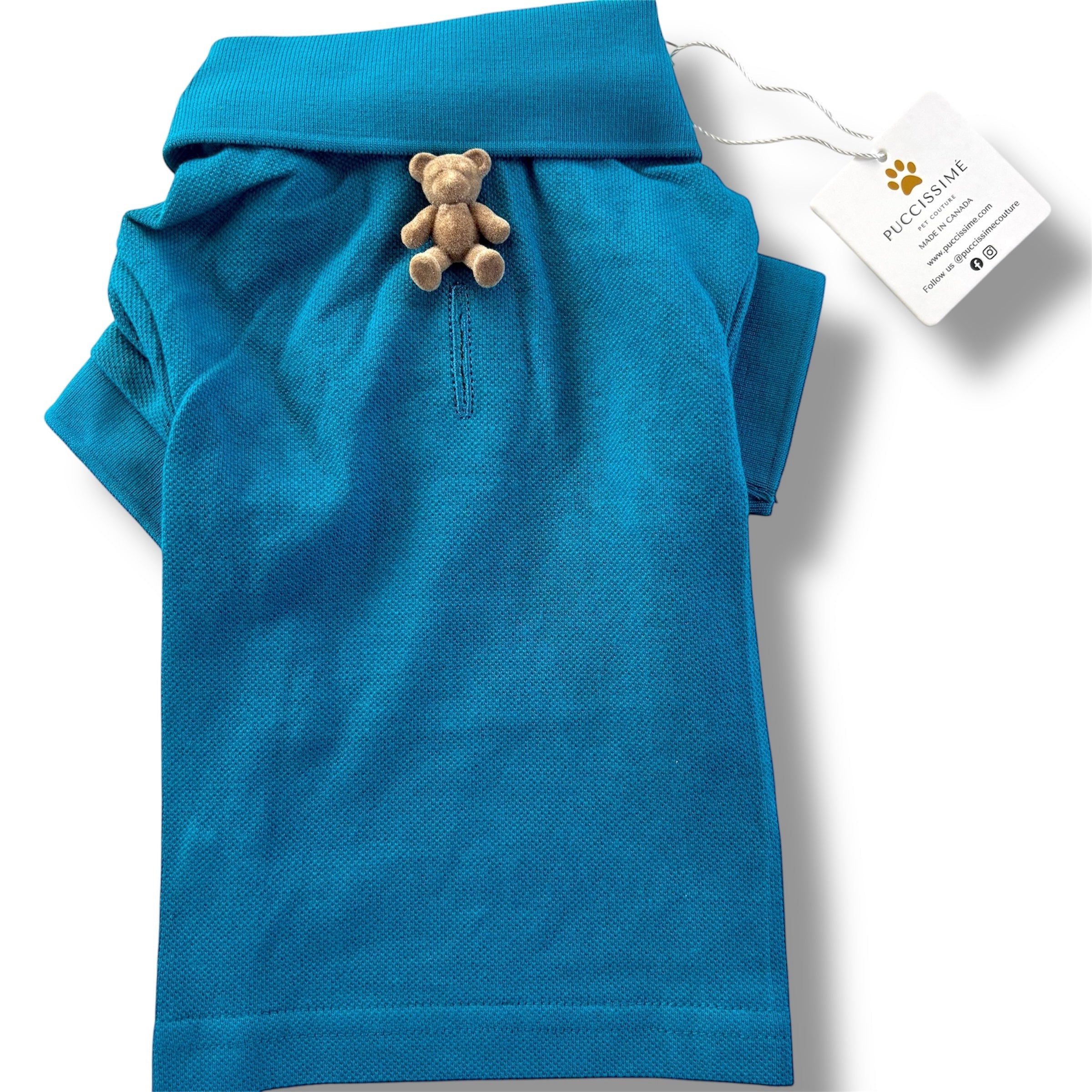 Blue dog shirt with a teddy bear toy and a tag on a white background