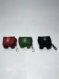 Three small pouches in red, green, and black with keychains on a light gray background