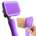 Purple pet grooming brush with a hand holding it on a white background