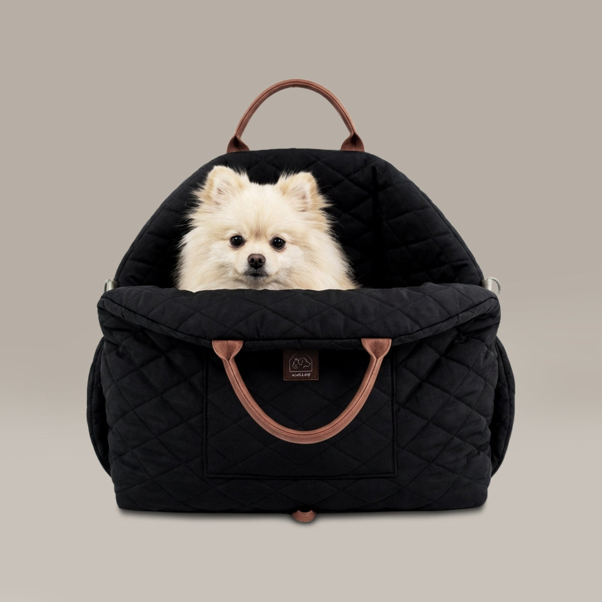 Black quilted pet carrier with a small white dog inside on a beige background