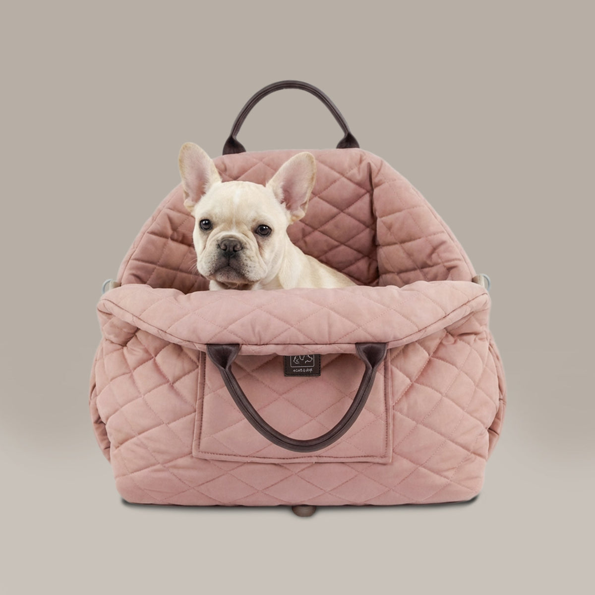 Pink quilted pet carrier with a small white dog inside on a beige background