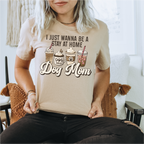 Person wearing a beige t-shirt with 'I Just Wanna Be a Stay at Home Dog Mom' text and graphics.