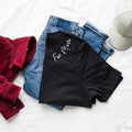 Black t-shirt with 'For Mom' text, red jacket, blue jeans, and gray cap on a white surface