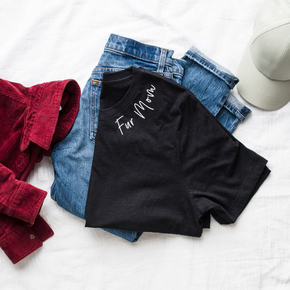 Black t-shirt with 'For Mom' text, red jacket, blue jeans, and gray cap on a white surface