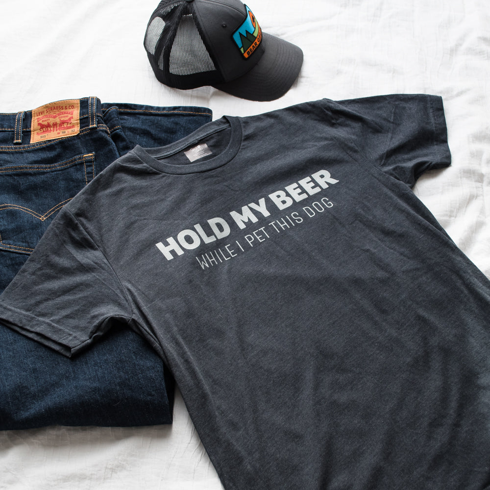 Gray t-shirt with humorous text hold my beer while i pet this dog, jeans, and cap on a white background