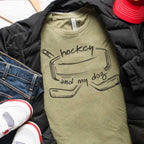 Green t-shirt with 'hockey and my dog' text and graphics on a pile of clothes.