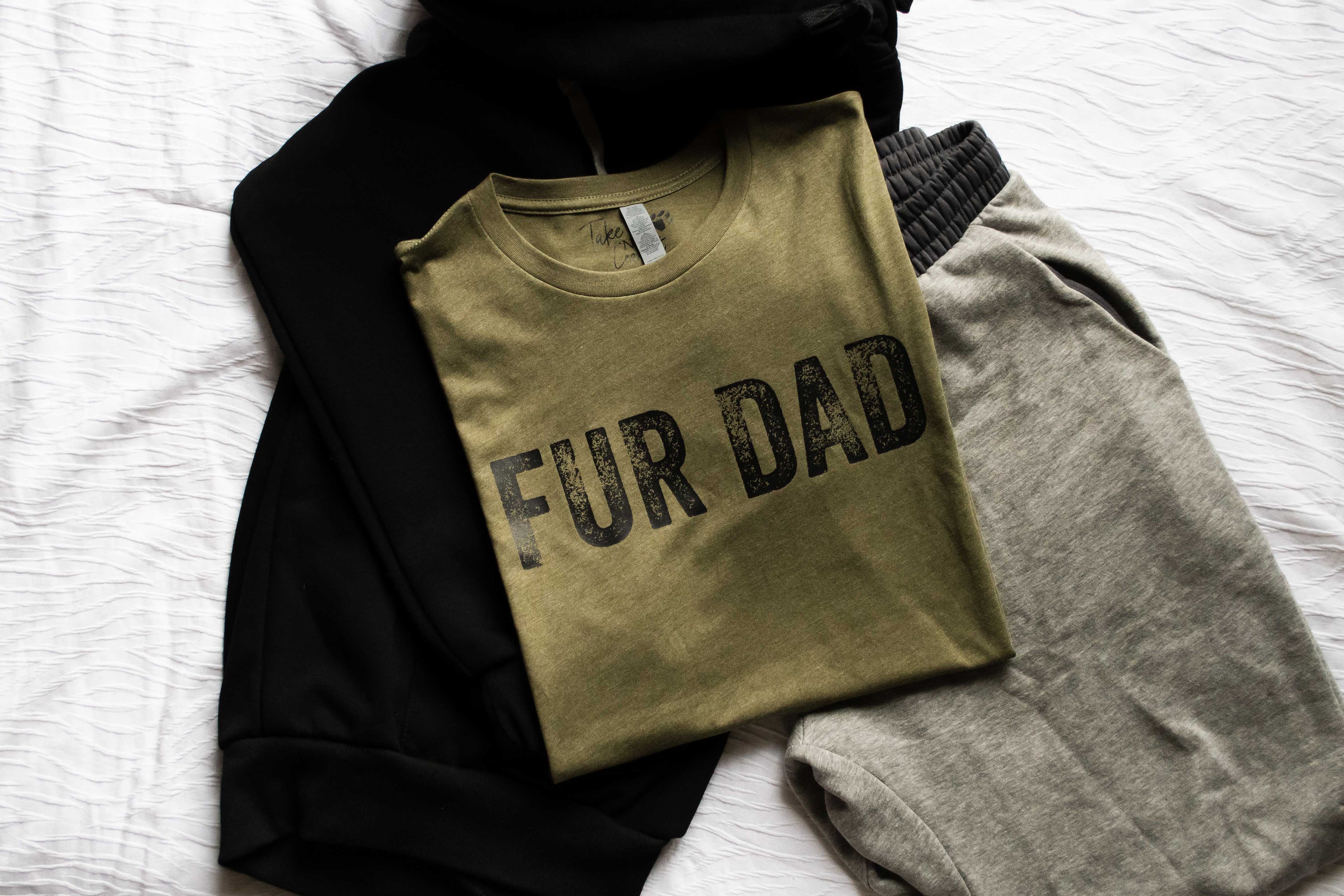 Folded sweatshirt with 'FUR DAD' text on a white surface