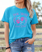Person wearing a blue t-shirt with 'Dog Mom Social Club' design outdoors.
