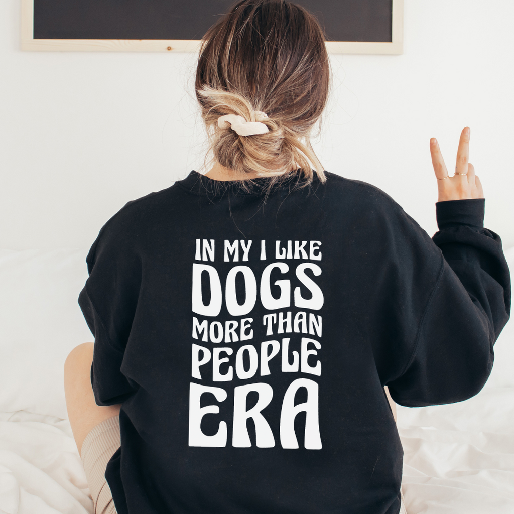 Person wearing a black sweatshirt with text on the back, sitting on a white couch.