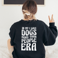 Person wearing a black sweatshirt with text on the back, sitting on a white couch.