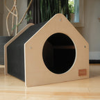 Wooden pet house with a circular entrance on a wooden floor.