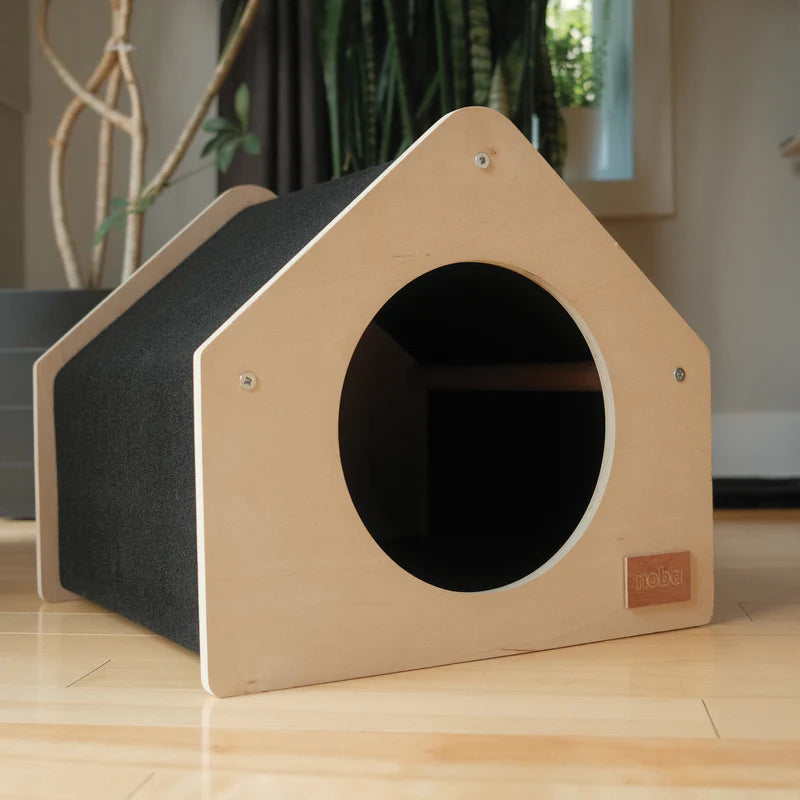 Wooden pet house with a circular entrance on a wooden floor.