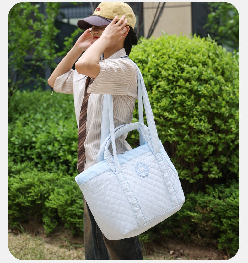 Person holding a white quilted pet carrier with greenery in the background