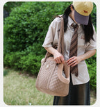 Person holding a quilted pet carrier outdoors with greenery in the background