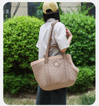 Person holding a beige pet carrier outdoors.