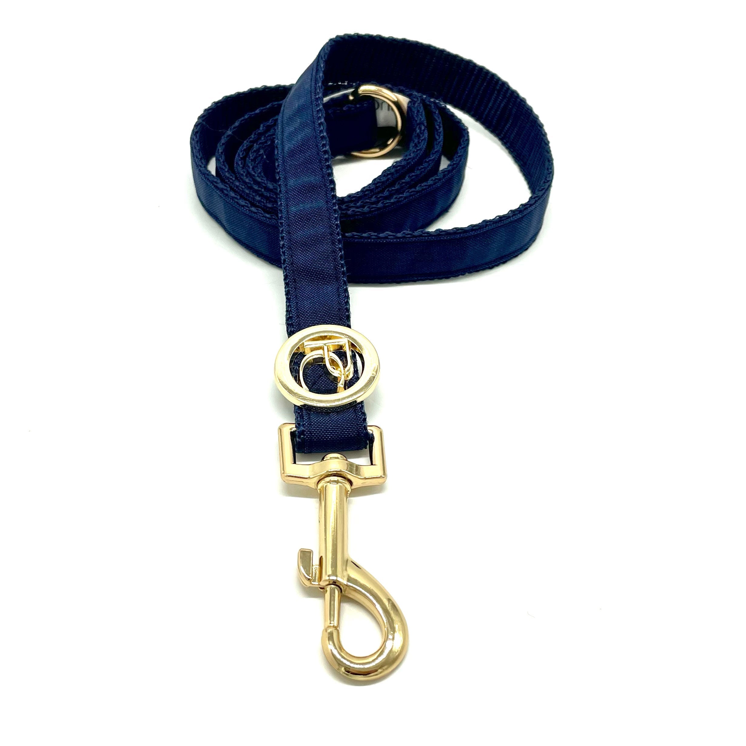 Navy blue dog leash with gold clasp on a white background