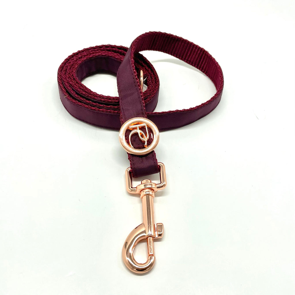 Burgundy dog leash with rose gold clasp on a white background
