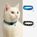 White cat wearing a blue collar with a bell, next to two additional collars on a white background.