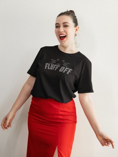 Woman wearing a black t-shirt with 'FLUFF OFF' text and red pants against a white background