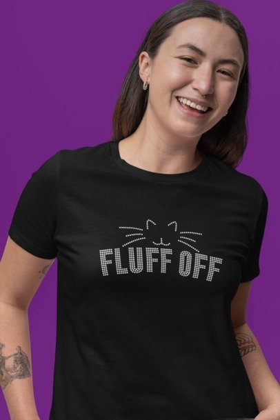 Person wearing a black t-shirt with 'FLUFF OFF' text and cat face design on a purple background