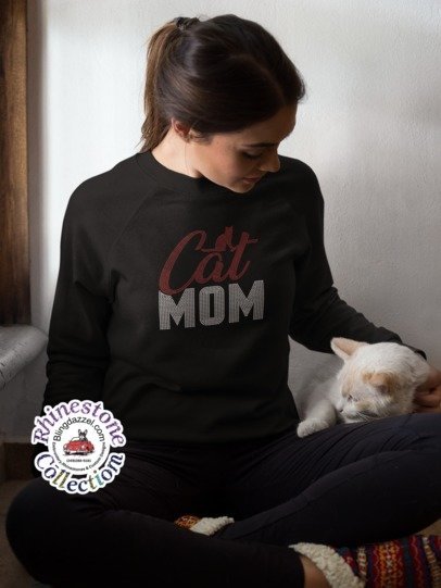 Woman wearing a black sweatshirt with 'Cat Mom' text, sitting with a cat.