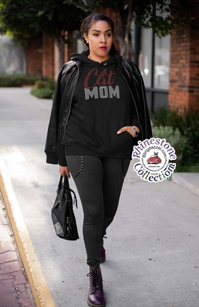 Woman wearing a black hoodie with 'CAT MOM' text, walking outdoors.