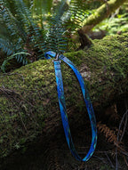 Blue dog leash on a mossy log in a forest setting