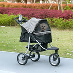 Pet stroller with a dog inside, parked on a pathway with greenery in the background