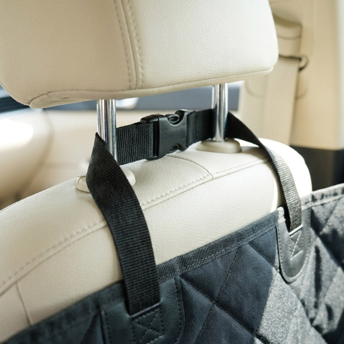 Car seat cover with a black strap attached to a car headrest.