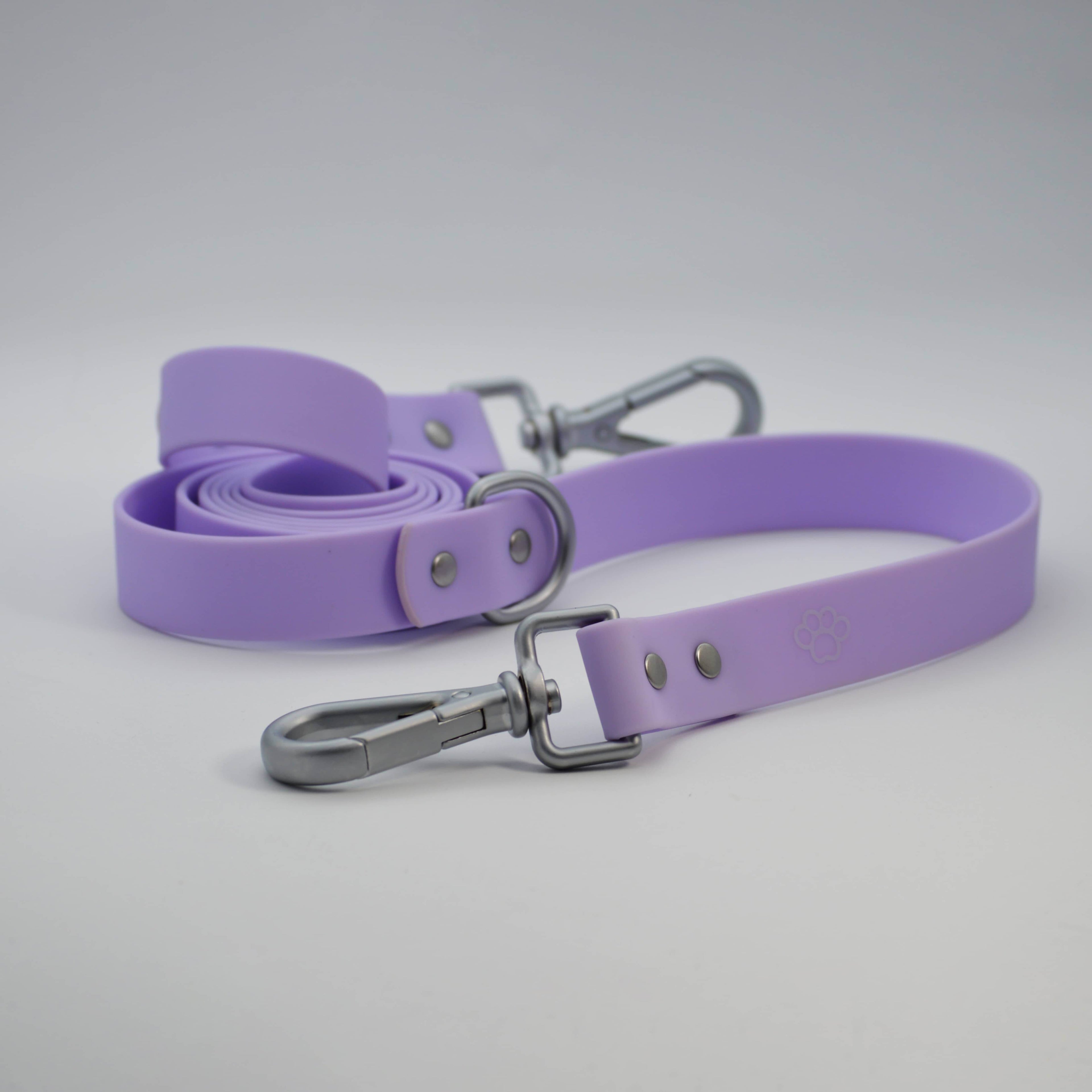 Purple dog leash with silver clips on a light gray background