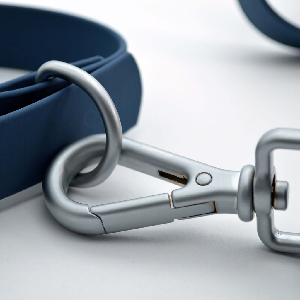 Close-up of a blue dog leash with a silver clasp on a light gray background