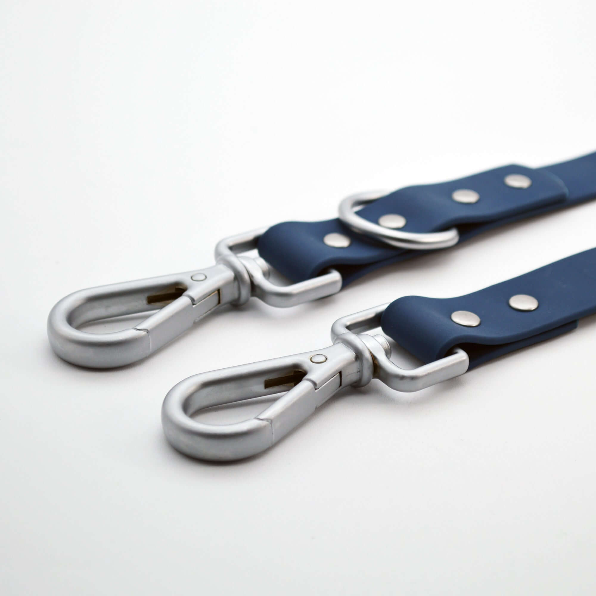 Two blue dog leash with silver hardware on a white background