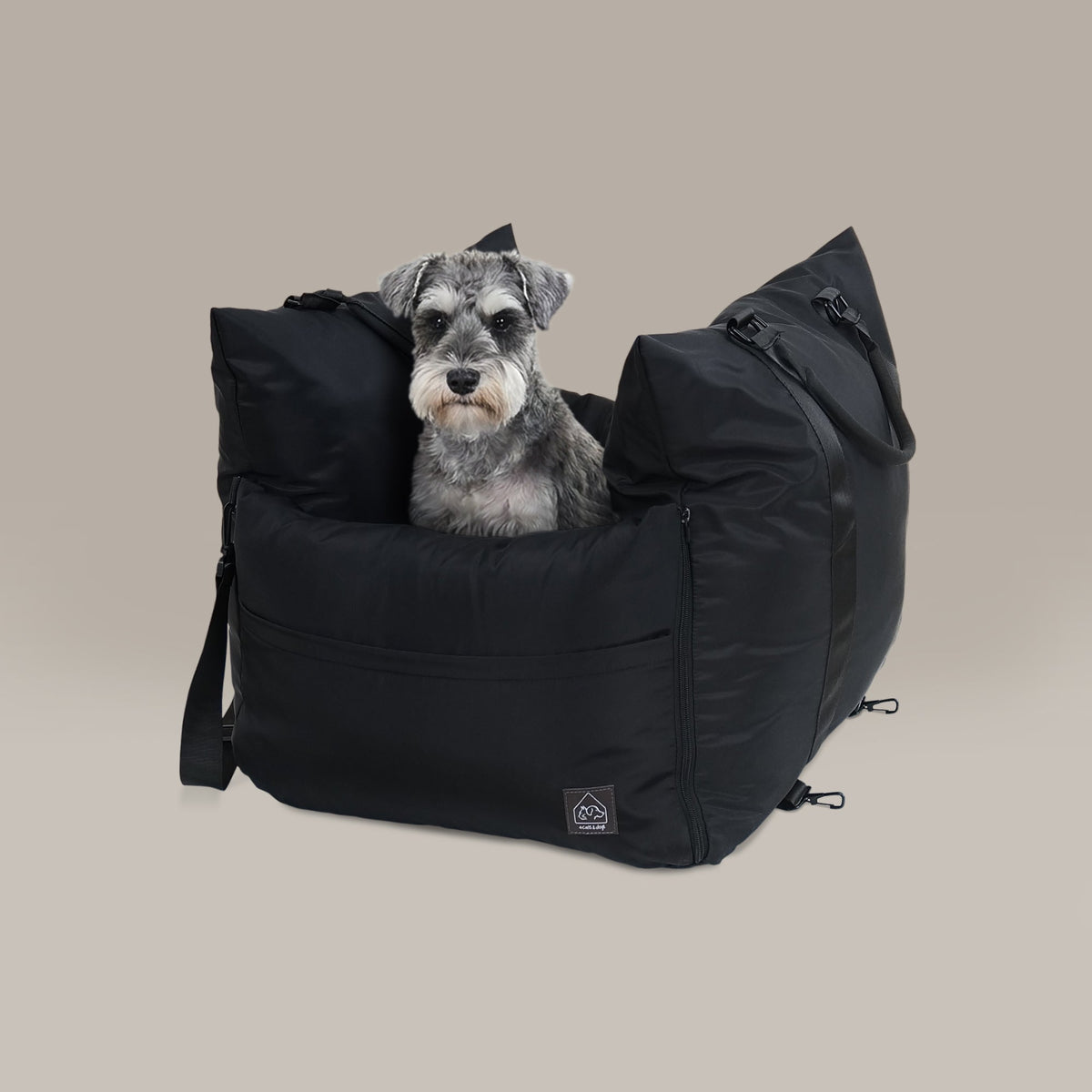 Dog sitting in a black pet carrier on a beige background