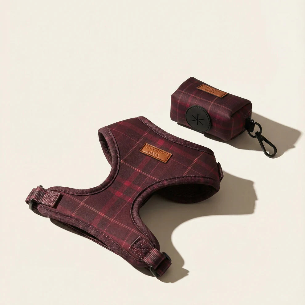 Red plaid dog harness and matching dog waste holder on a beige background