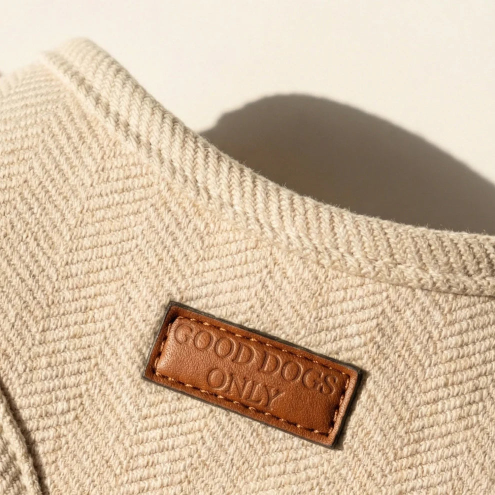 Beige dog harness with a brown leather label reading 'Good Dogs Only' on a light background