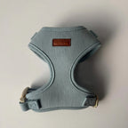 Light blue dog harness with a brown leather patch on a light gray background