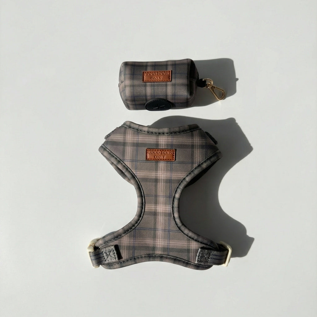 Plaid dog harness and a dog waste bag pouch on a light gray background