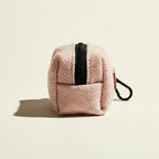 Pink textured dog waste bag holder with a black zipper on a beige background