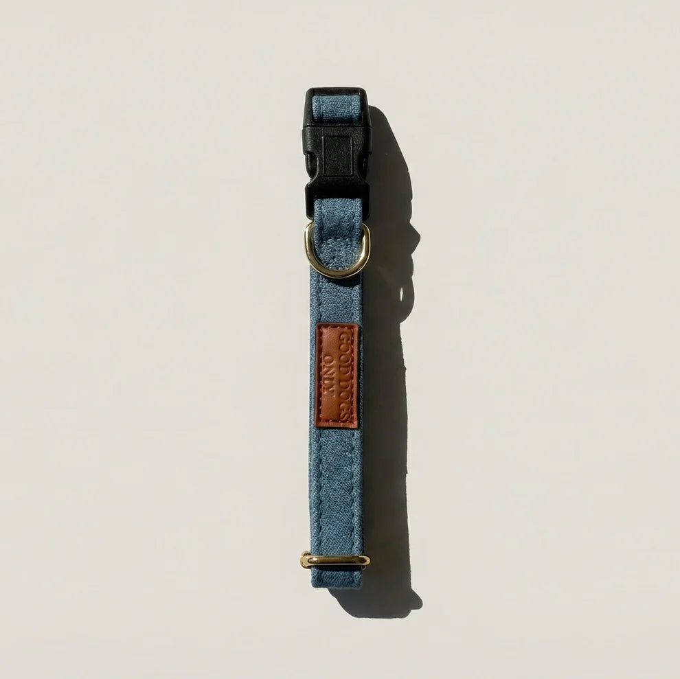 Blue dog collar with brown leather patch on a light beige background