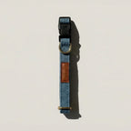 Blue dog collar with brown leather patch on a light beige background