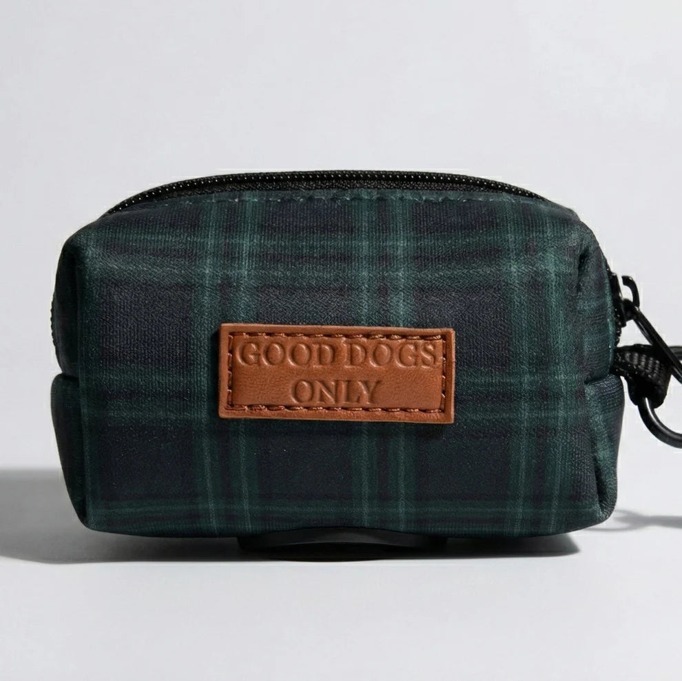 Green plaid dog waste bag holder with a brown leather patch labeled 'Good Dogs Only' on a light gray background