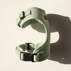 Green dog harness with black buckles on a beige background