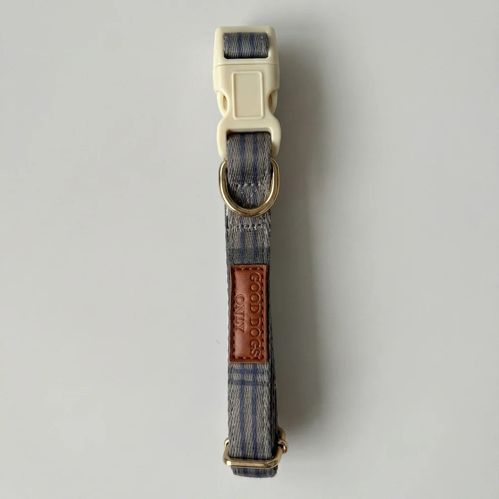 Dog collar with blue plaid pattern and brown leather patch on a gray background