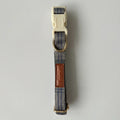 Dog collar with blue plaid pattern and brown leather patch on a gray background